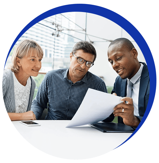 Three people are sitting at a table looking at papers.