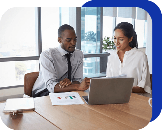 Two people sitting at a table looking at a laptop.